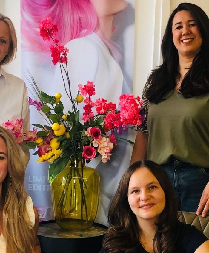 Bloemboeket in de salon van Koele Coupe, met het team op de achtergrond.